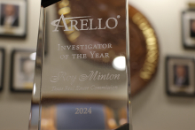 A closeup photo of the Investigator of the Year award. It's a crystal structure with engraved lettering. The TREC seal is in the background blurred. 