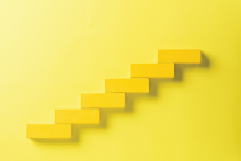 Yellow wooden blocks stacked as stair steps are on a yellow background